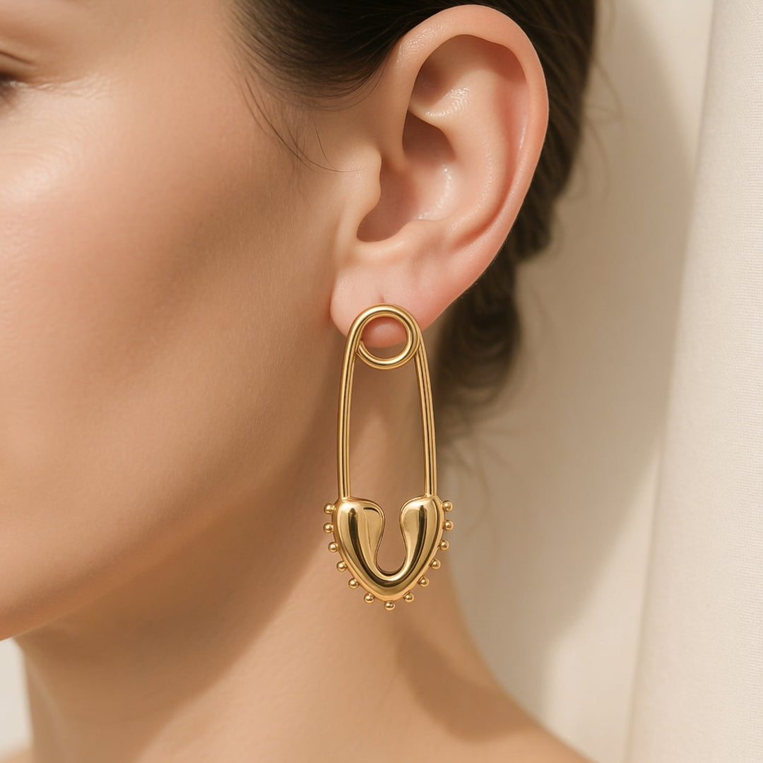 Gold safety pin shaped water resistant earring worn on a woman&