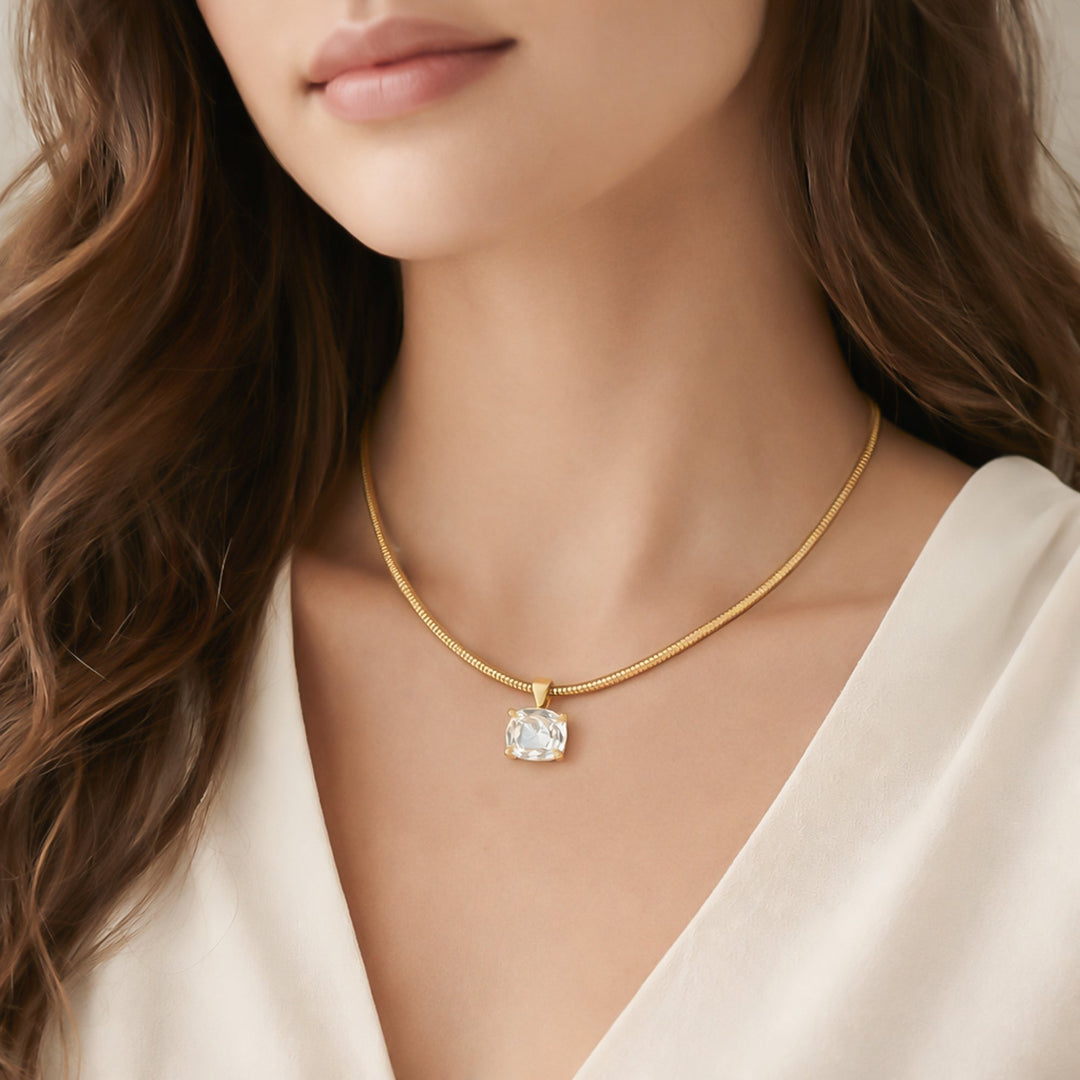 Gold snake chain necklace with large cushion-cut clear crystal pendant worn by model