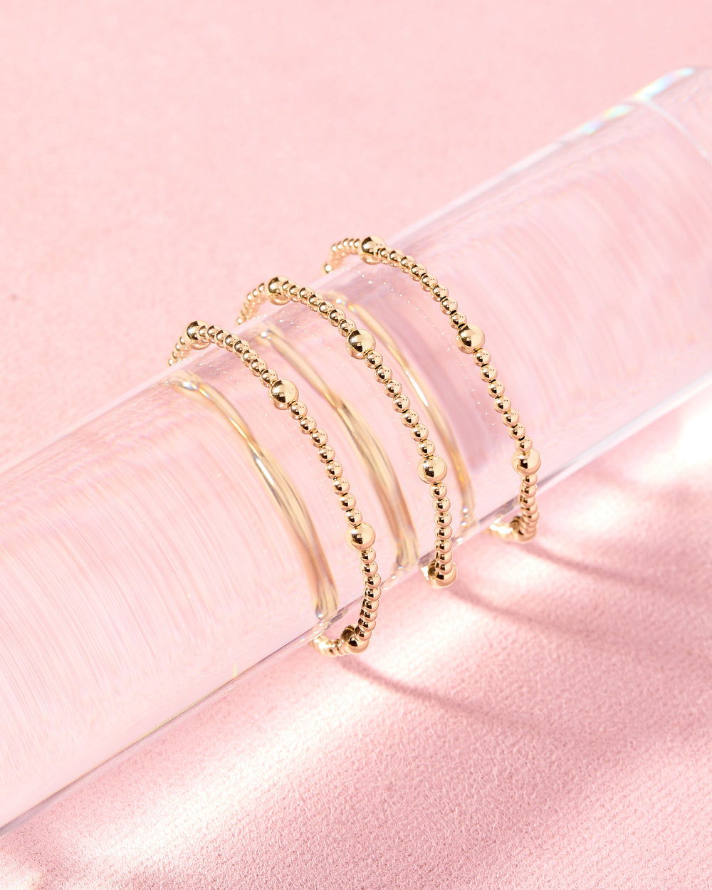 Beaded Blondes Olive Bracelet in gold, featuring mixed bead sizes on elastic cord, styled in a stack of four on a clear ac...