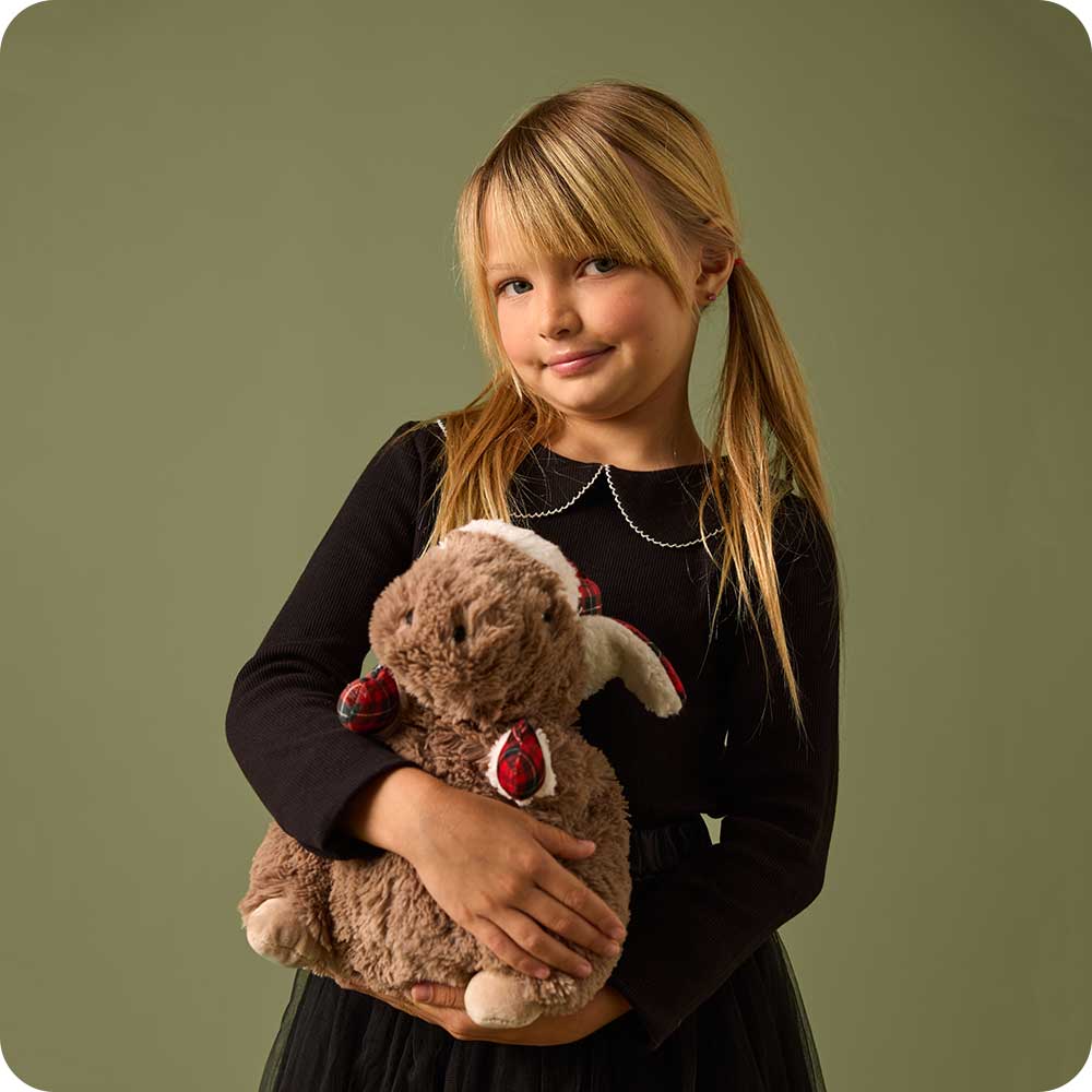 Young girl holding brown Warmies Cozy Capybara plush toy against olive background