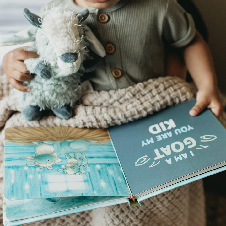 Child holding Bunnies by the Bay 'You Are My Baby' board book with goat plush toy