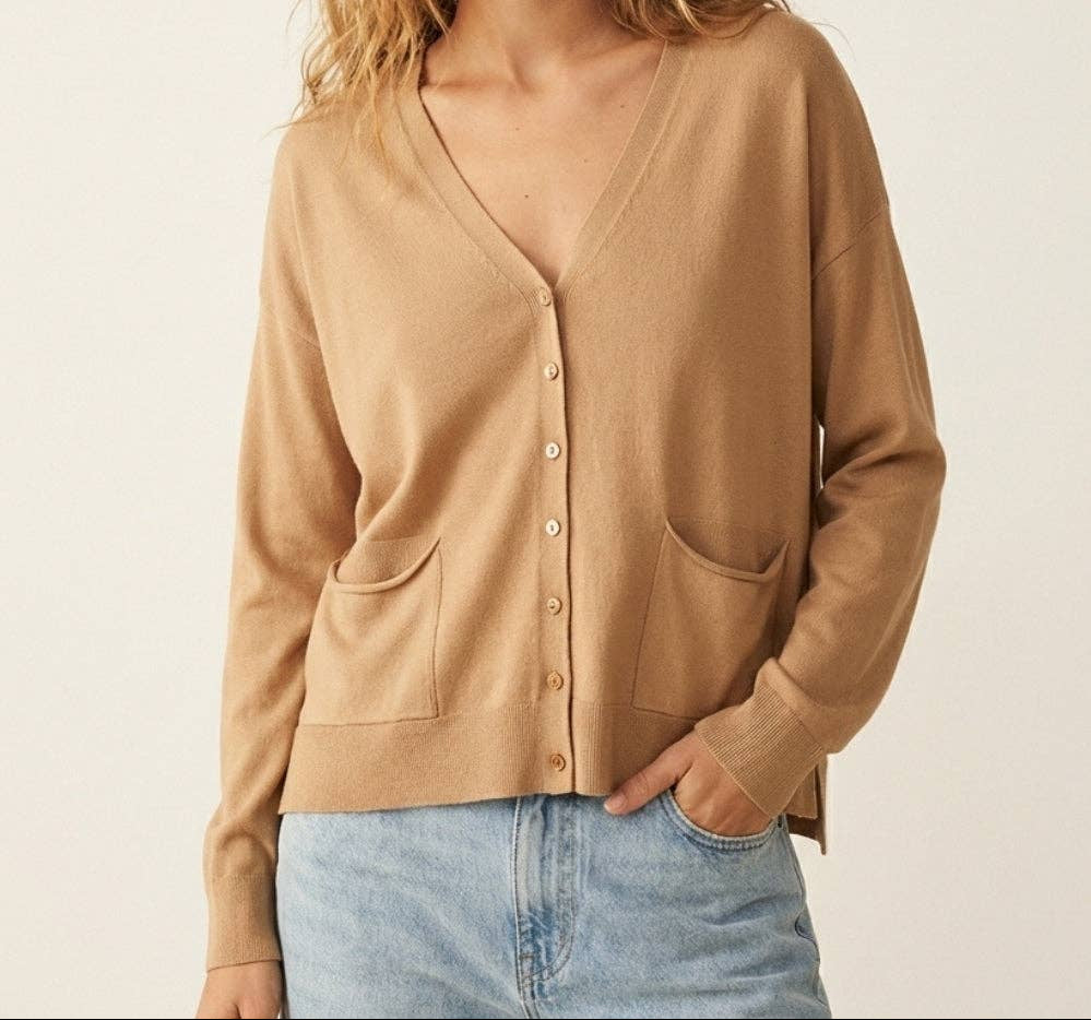 Woman wearing camel colored fine knit button-front cardigan with two front pockets