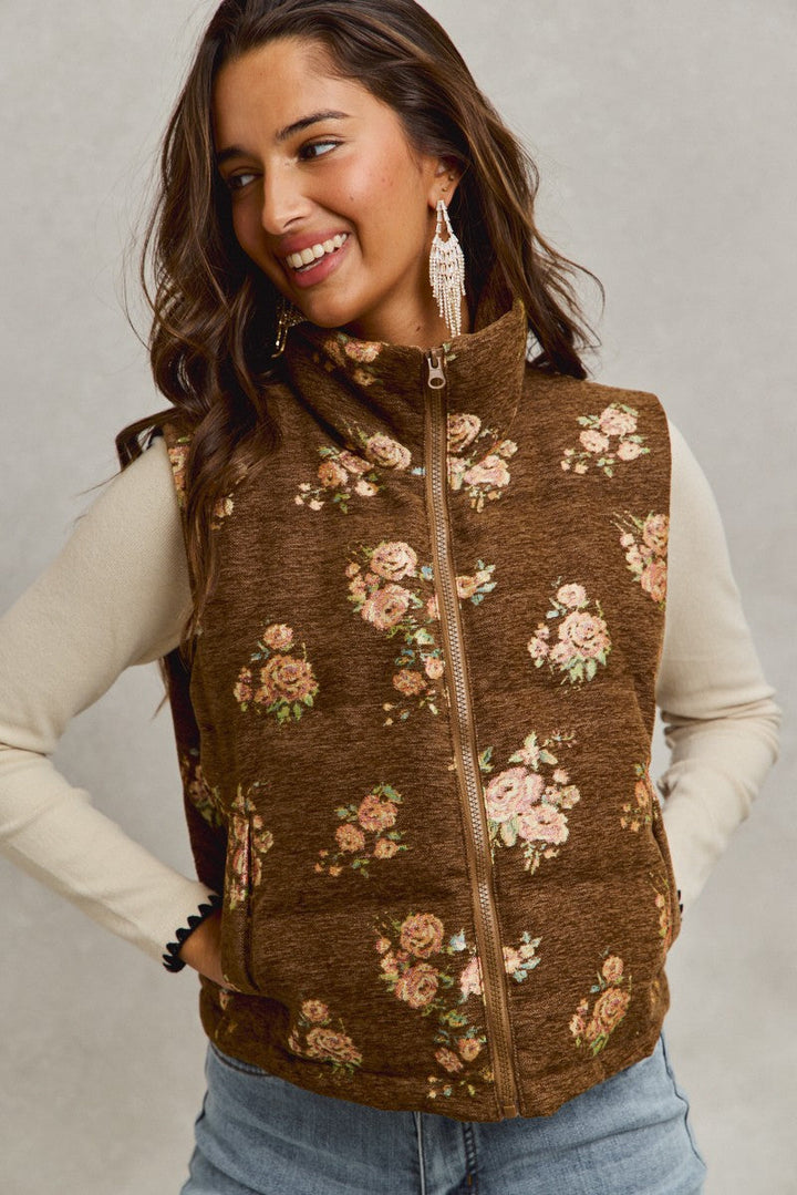 Woman wearing brown floral jacquard quilted vest with pink roses over cream long sleeves