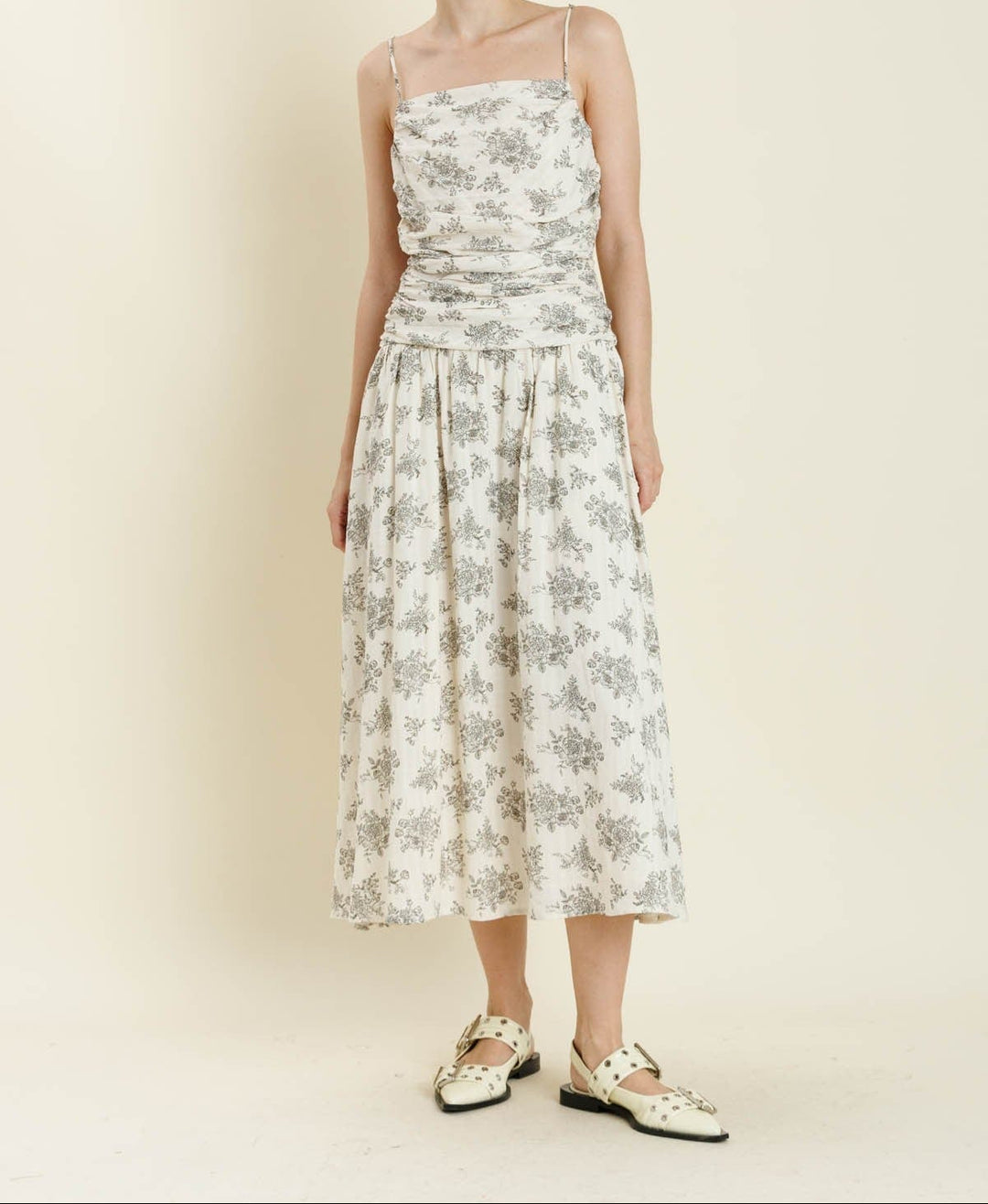 Woman wearing ivory floral midi dress with spaghetti straps and shirred bodice