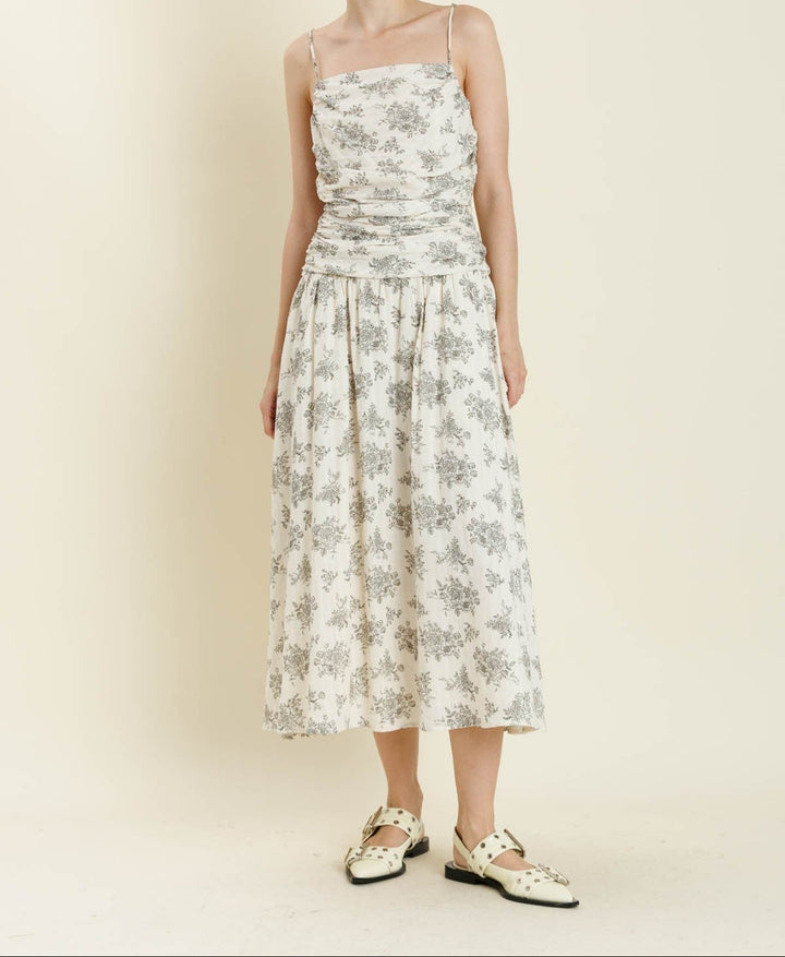 Woman wearing ivory floral midi dress with spaghetti straps and shirred bodice