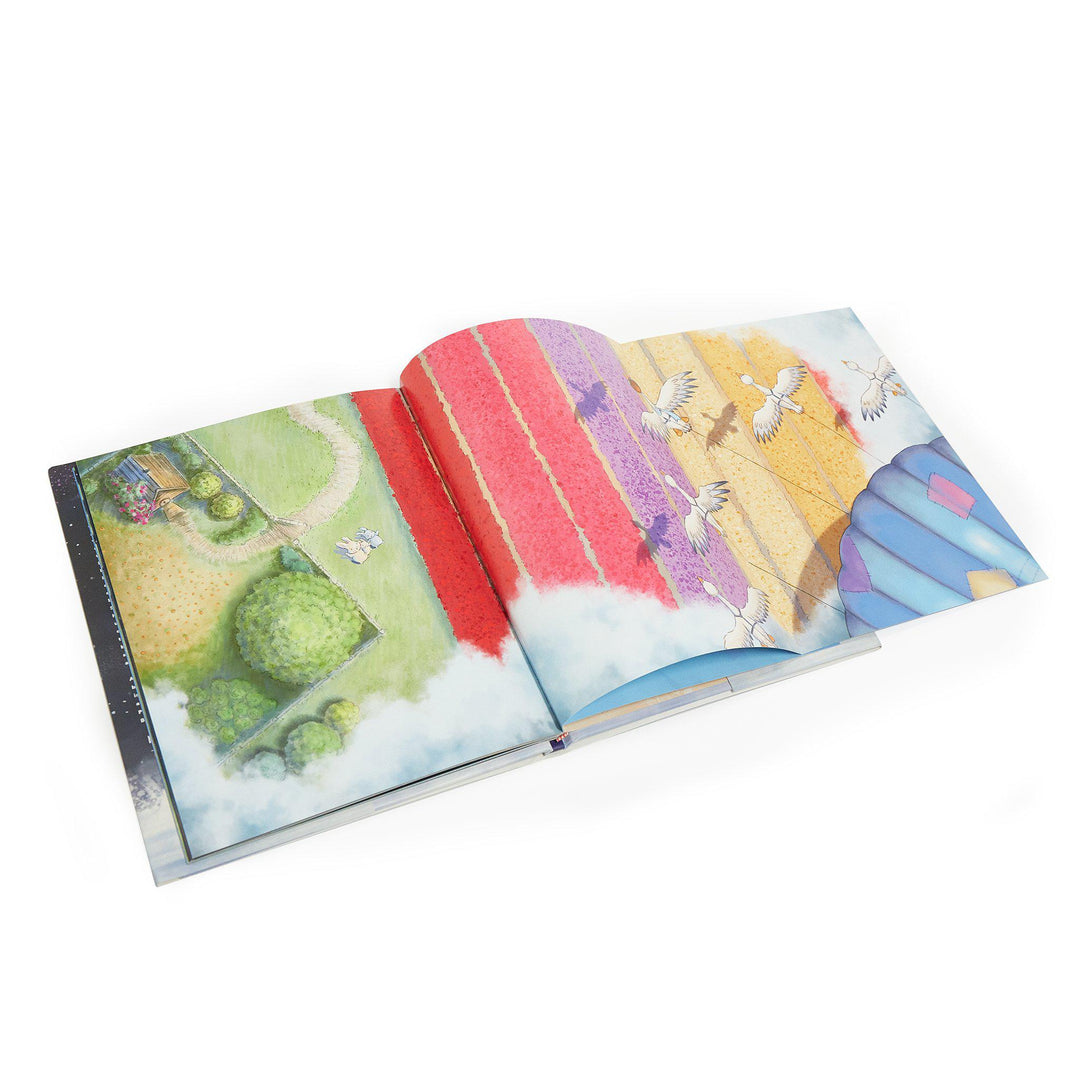 Open storybook showing colorful illustrated spread of garden, flower fields, and flying cranes