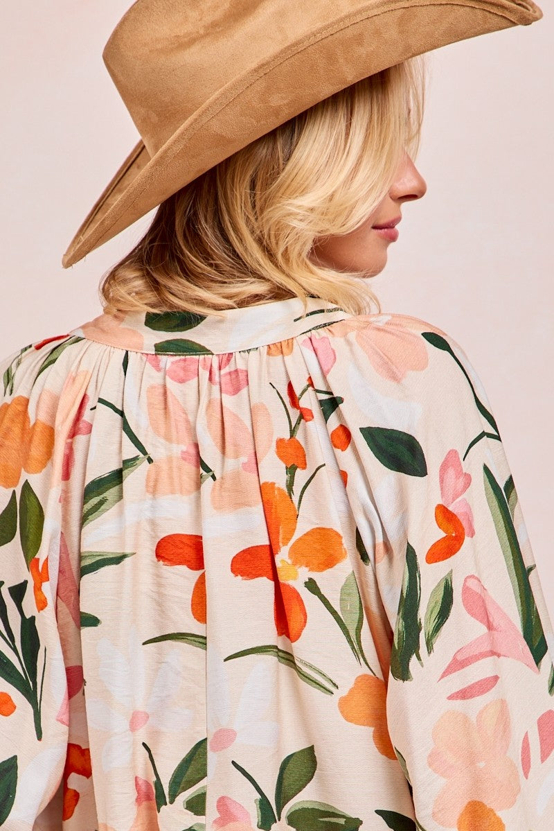 Woman wearing floral print balloon sleeve top with orange and pink flowers on cream background