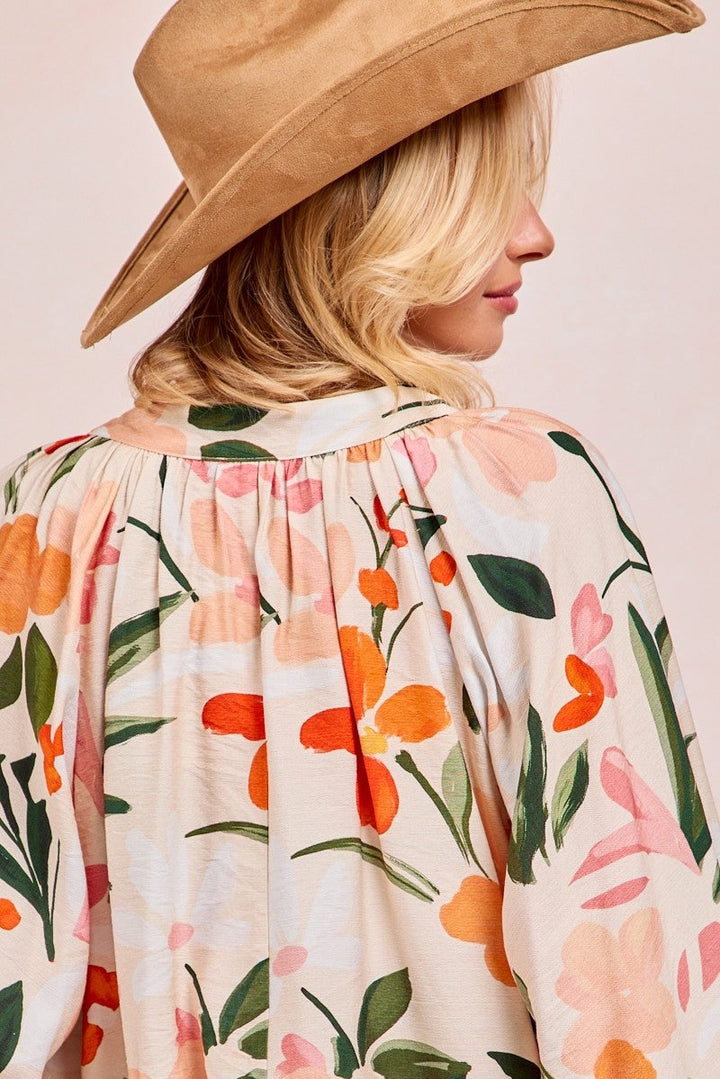 Woman wearing floral print balloon sleeve top with orange and pink flowers on cream background