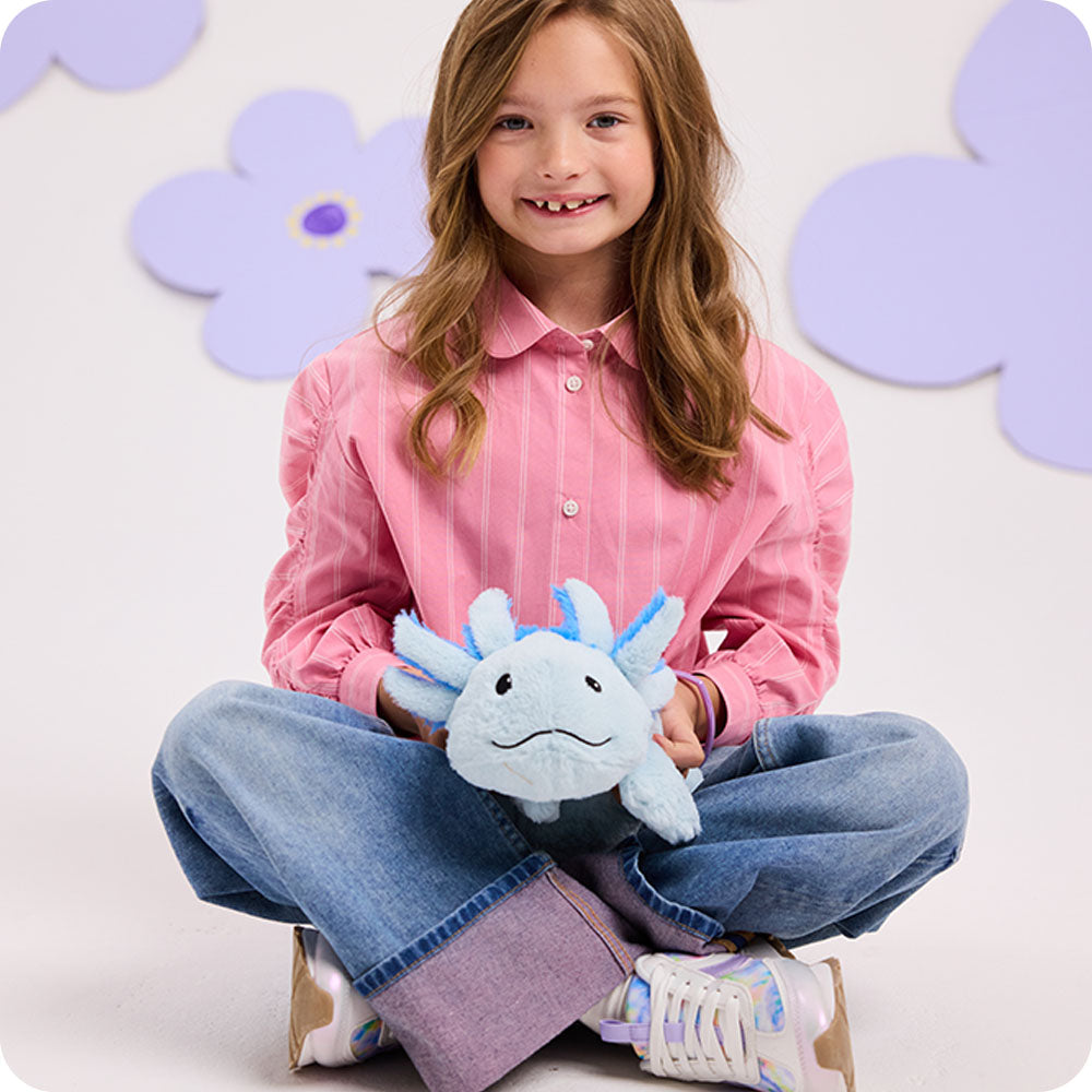 Child holding light blue Warmies axolotl plush toy with decorative flower background