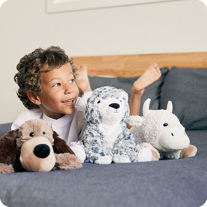 Child with Warmies stuffed animals including white buffalo with blue marbled pattern