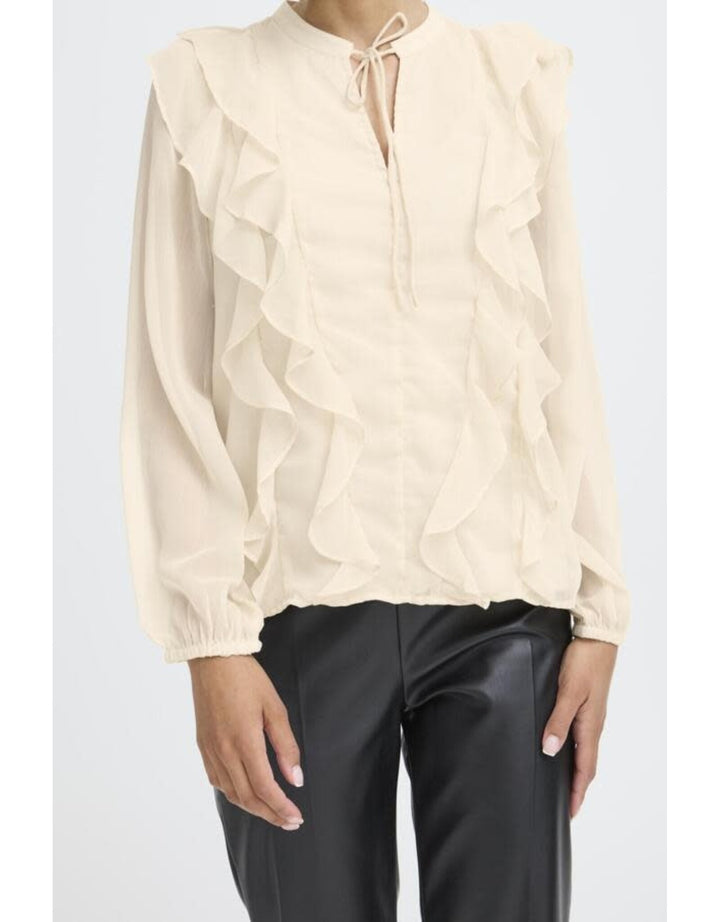 Cream colored ruffled blouse with tie neck and long sleeves paired with black pants