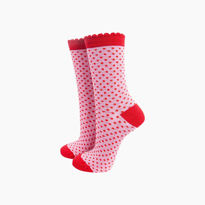 Pink crew socks with red polka dots, scalloped cuff, and red heel and toe accents