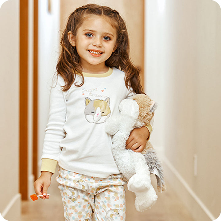 Child holding Warmies plush calico cat stuffed animal with gray white brown coloring
