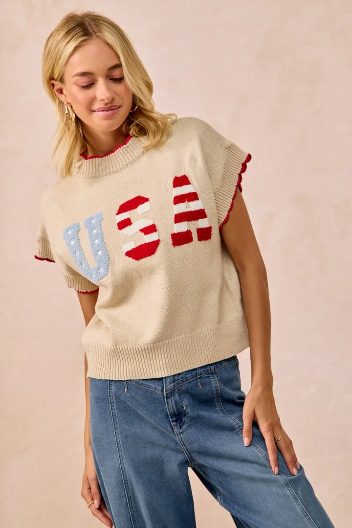 Woman wearing oatmeal sleeveless sweater vest with red white blue USA patchwork design
