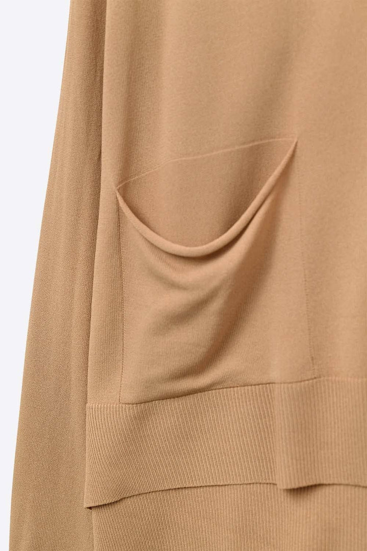 Close-up of camel colored fine knit cardigan showing front pocket detail and ribbed hem