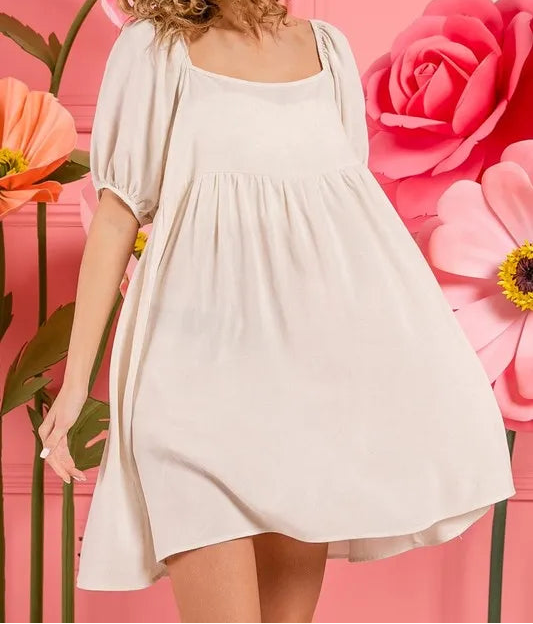 Woman wearing light beige tiered midi dress with puff sleeves against floral background