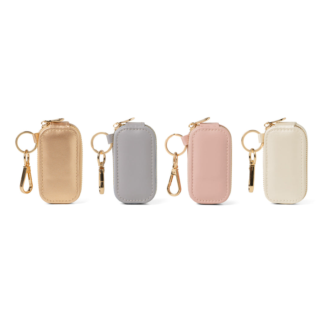 Four small leather keychains with gold hardware in gold, gray, pink, and cream colors
