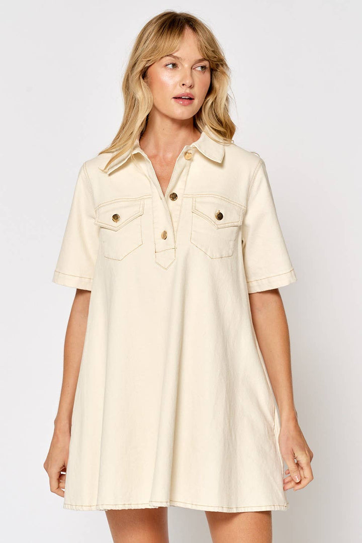 Cream colored short sleeve button down shirt dress with chest pockets and gold buttons