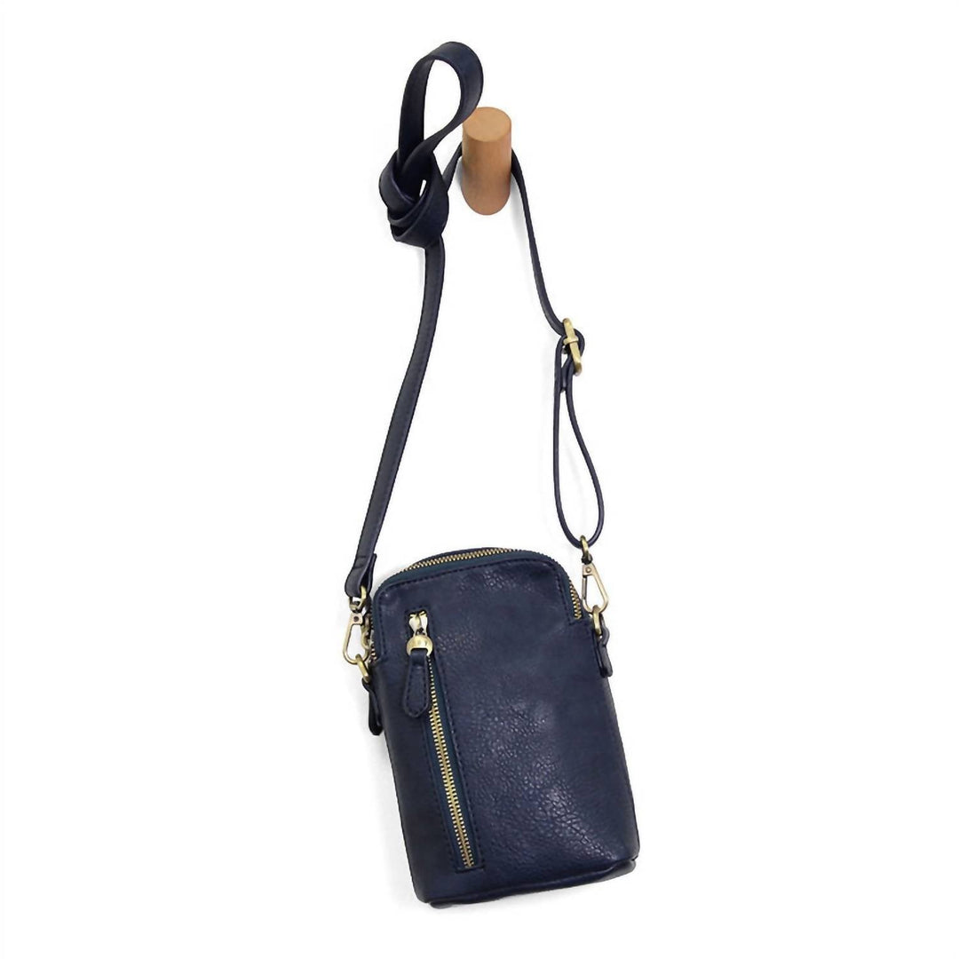 Navy vegan leather crossbody phone bag with gold zippers hanging on wooden hook