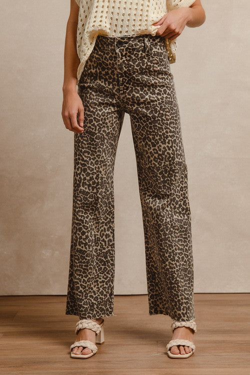 Woman wearing leopard print high-rise flare jeans with white eyelet top and beige sandals