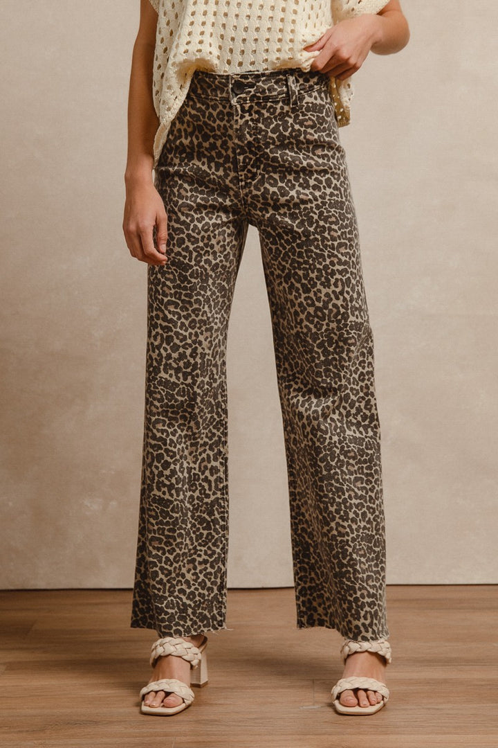 Woman wearing leopard print high-rise flare pants with cream eyelet top and neutral sandals