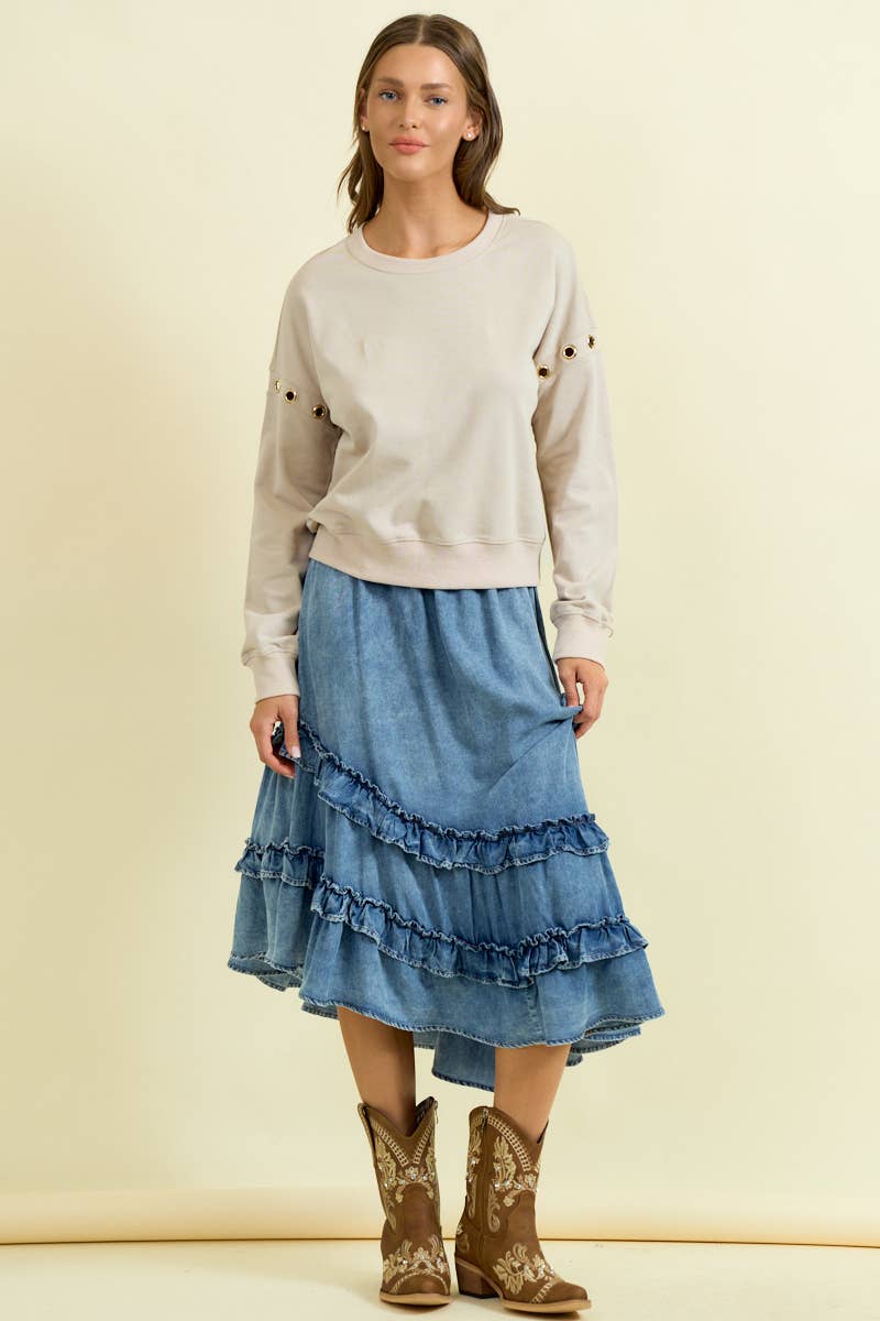 Woman wearing denim asymmetrical ruffle midi skirt with tiered ruffles and cowboy boots