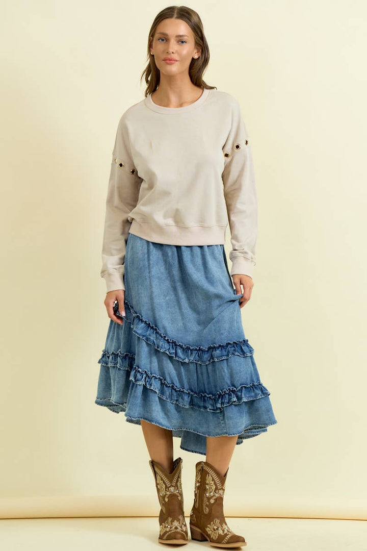 Woman wearing denim asymmetrical ruffle midi skirt with tiered ruffles and cowboy boots