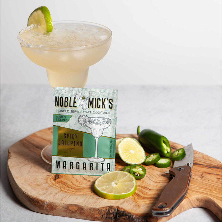 Noble Mick's Spicy Jalapeño Margarita single serve craft cocktail packet with finished drink and fresh limes