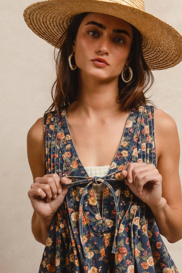 Woman wearing denim blue floral romper with tie waist and straw hat