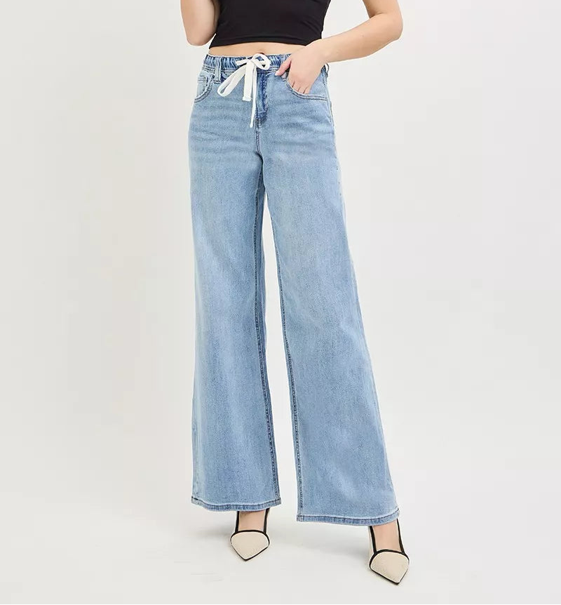 Woman wearing light wash wide leg jeans with drawstring and black camisole top