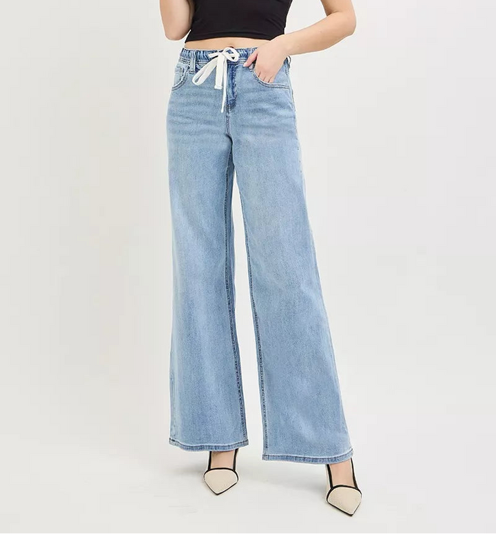 Woman wearing light wash wide leg jeans with drawstring and black camisole top