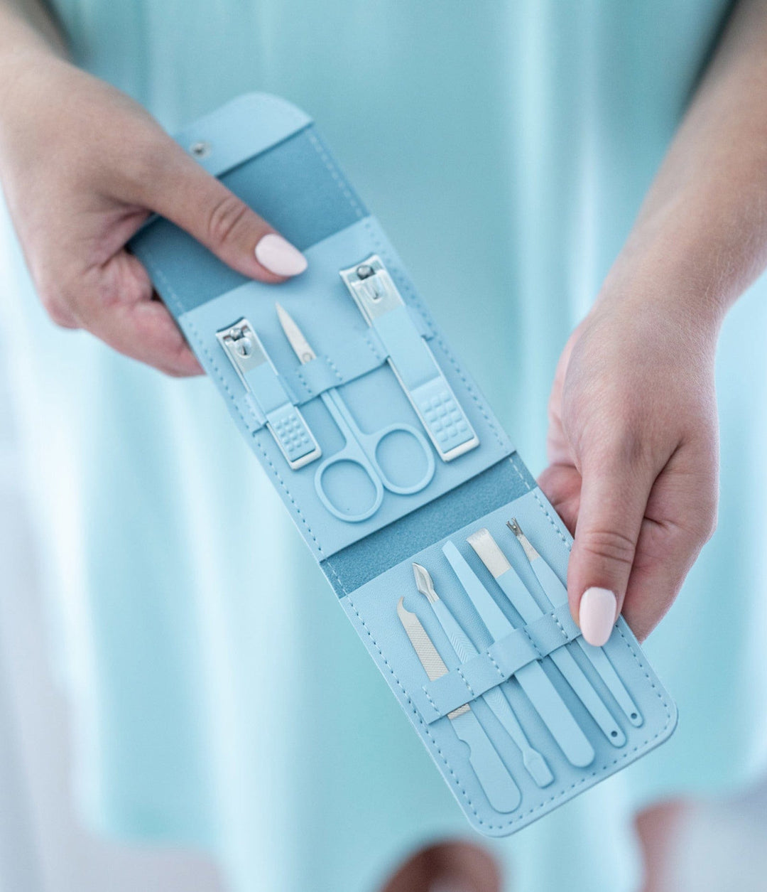 Light blue nail care kit with manicure tools displayed in hands