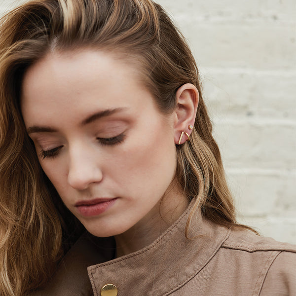 Woman wearing Scout Stud Trio gold earrings with multiple geometric studs