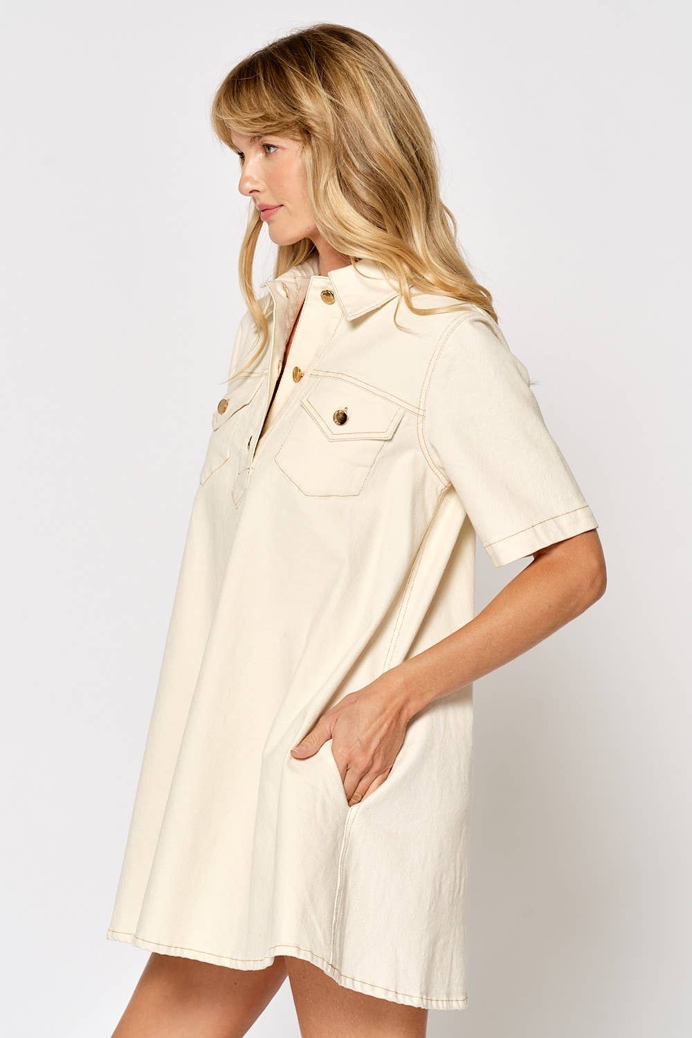 Woman wearing cream short sleeve button down shirt dress with collar and chest pockets