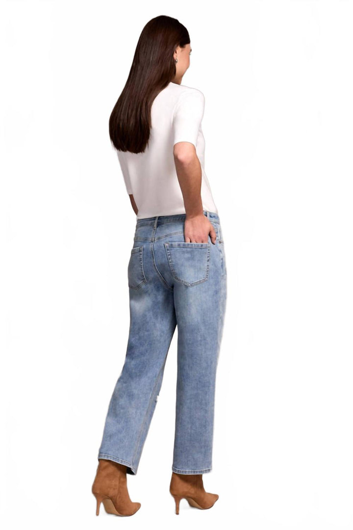 Woman wearing light washed blue straight leg flood jeans with white top, back view