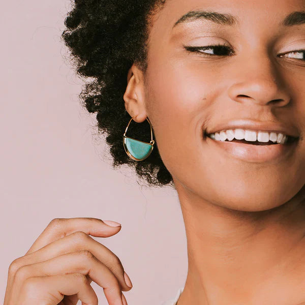 Woman wearing Scout Stone Prism Hoop earrings in turquoise and gold, smiling