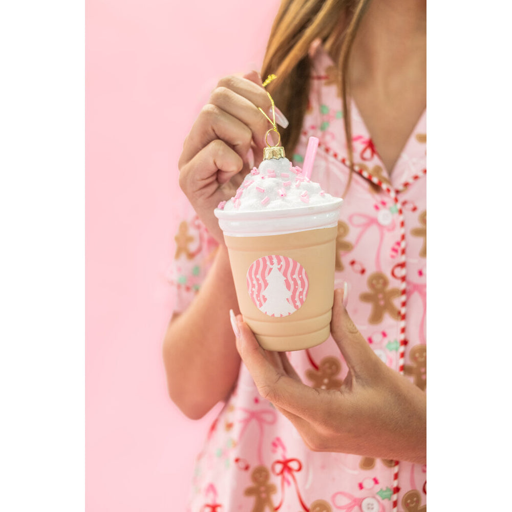 Hand holding a frappe coffee Christmas ornament with whipped cream and pink straw