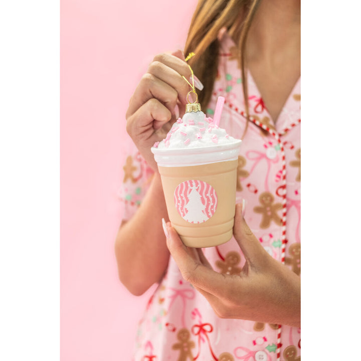 Hand holding a frappe coffee Christmas ornament with whipped cream and pink straw