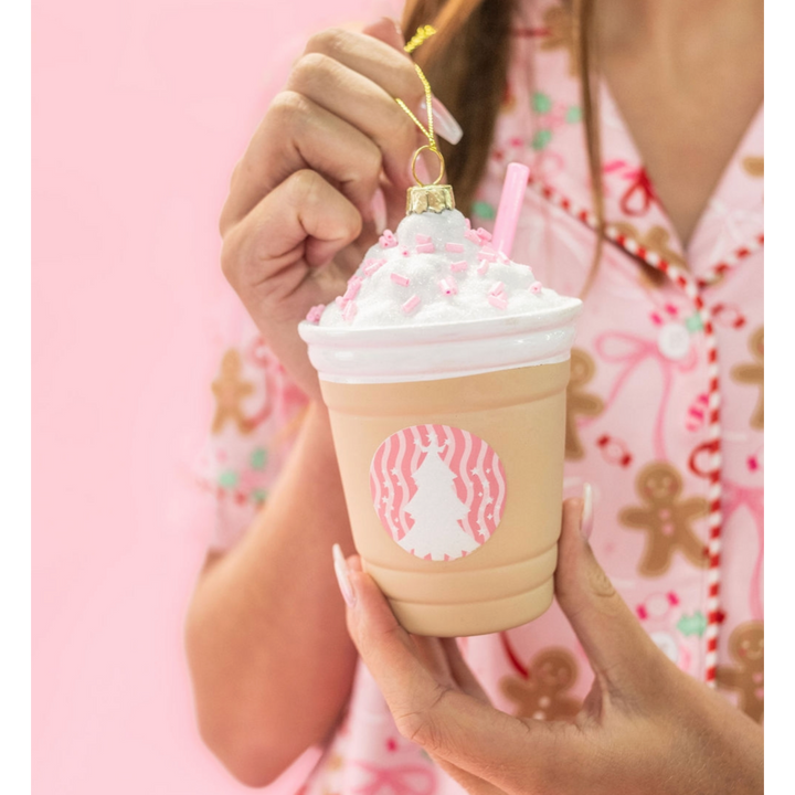 Hand holding a frappe coffee Christmas ornament with whipped cream and pink sprinkles topping