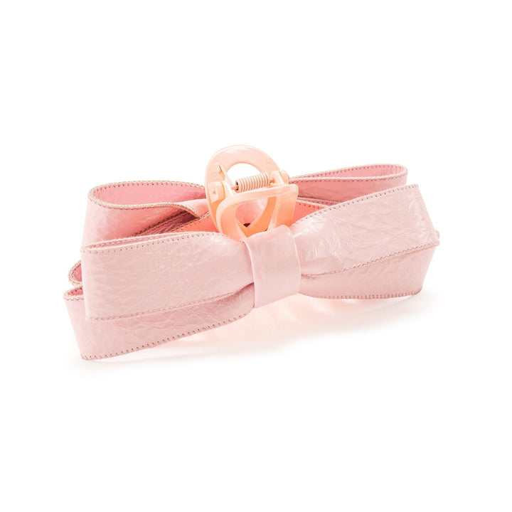 Pink bow hair accessory with spring-loaded clip closure on white background