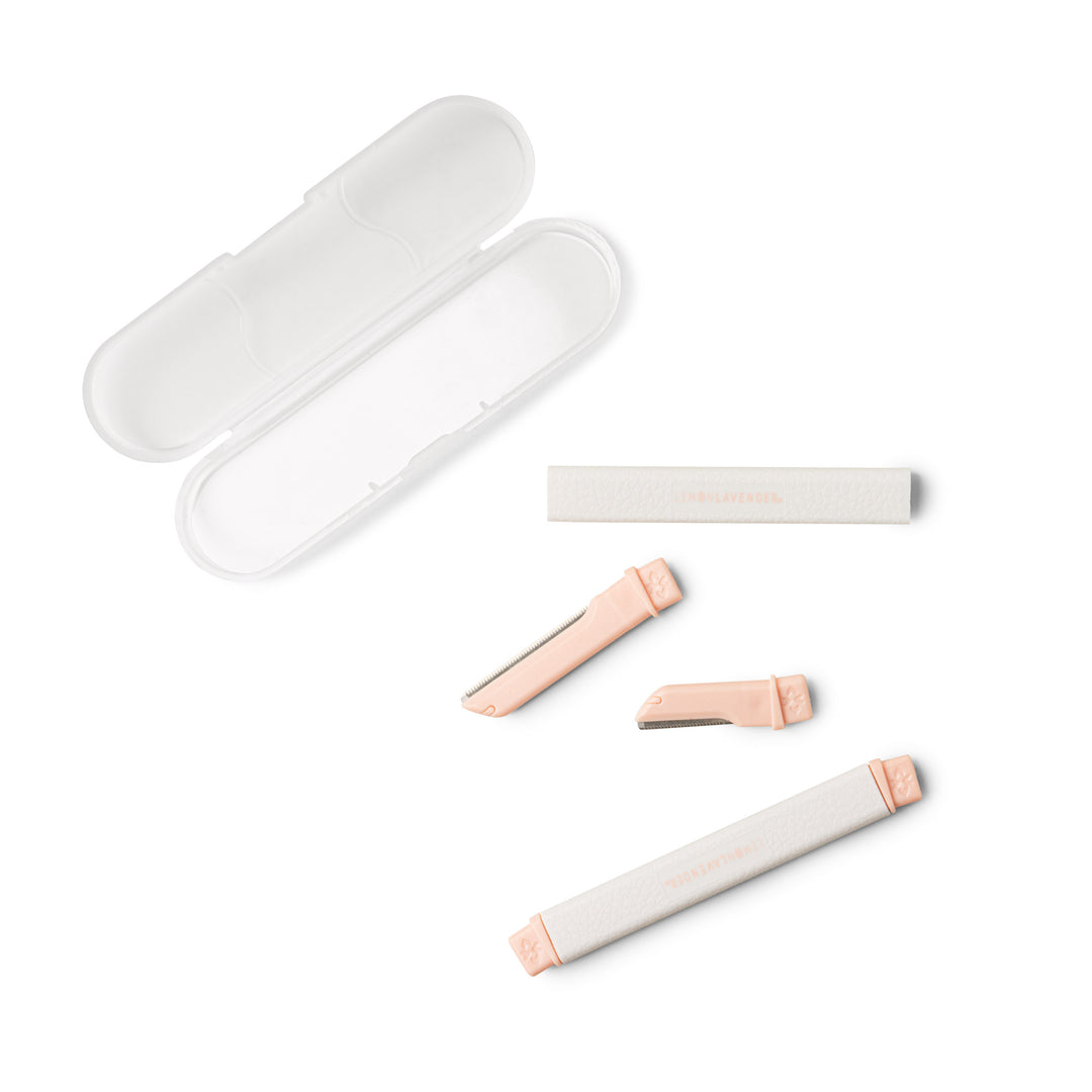 Dermaplaner facial razors with coral pink handles and clear protective case on white background