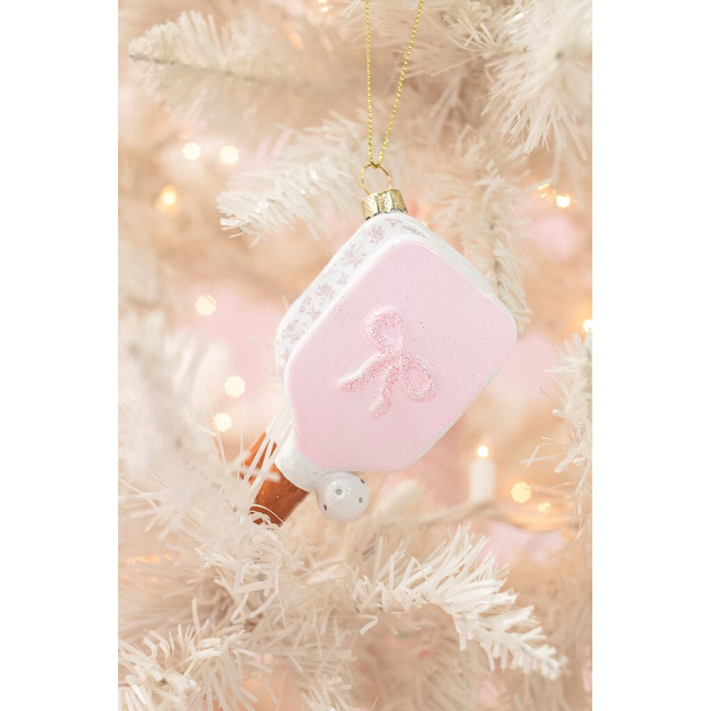 Pink pickleball paddle Christmas ornament with bow detail hanging on white tree