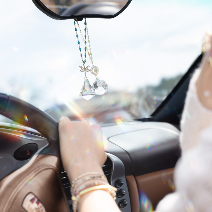 Scout suncatcher with teal beaded chain, crystal pendant and dragonfly charm hanging from car rearview mirror