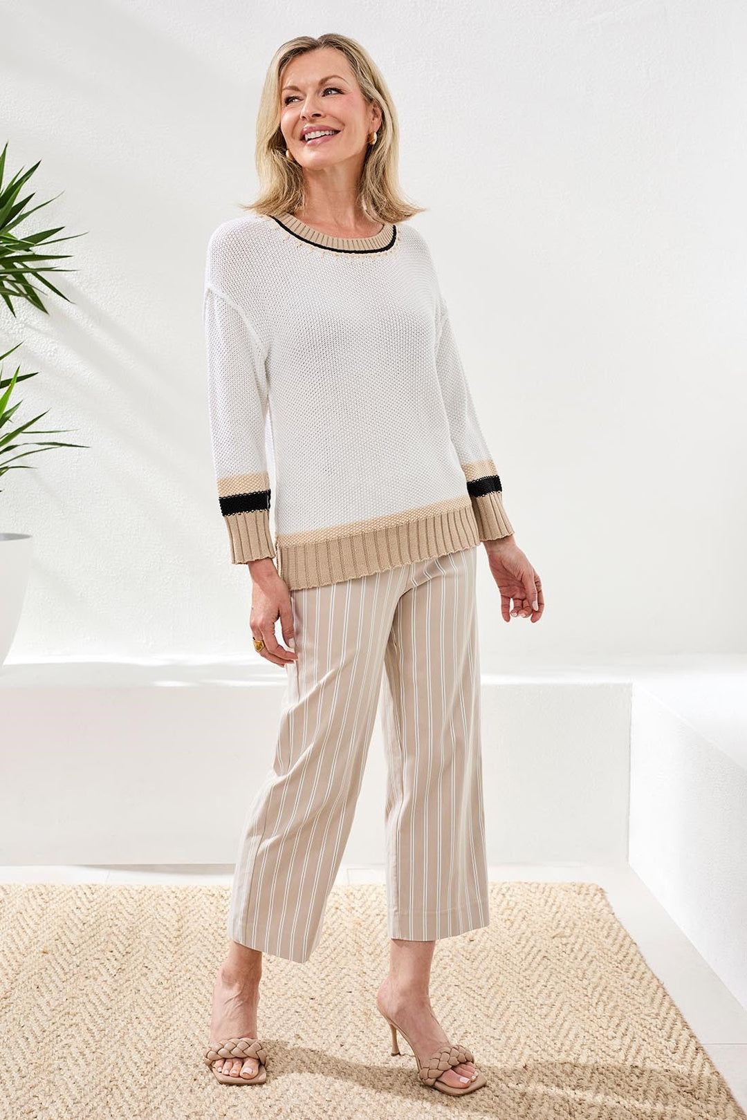 Woman wearing white crew neck sweater with tan and black trim details