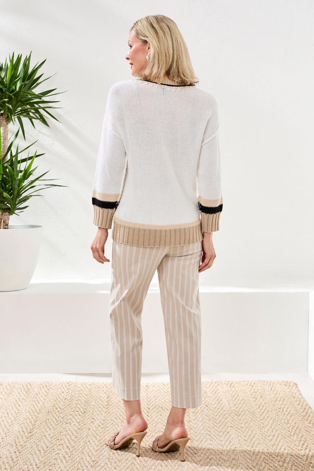 Woman wearing light gray 3/4 sleeve crew neck sweater with striped trim detail