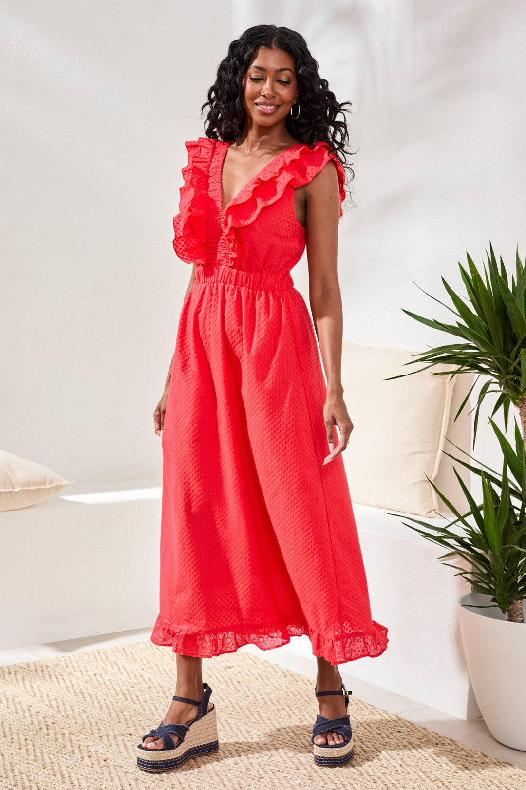 Woman wearing bright coral red ruffle maxi dress with v-neck and tiered hem