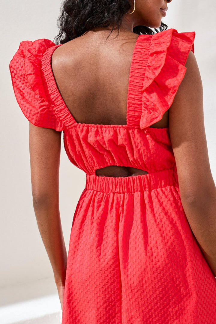 Coral red maxi dress with ruffled shoulders and open back detail on model