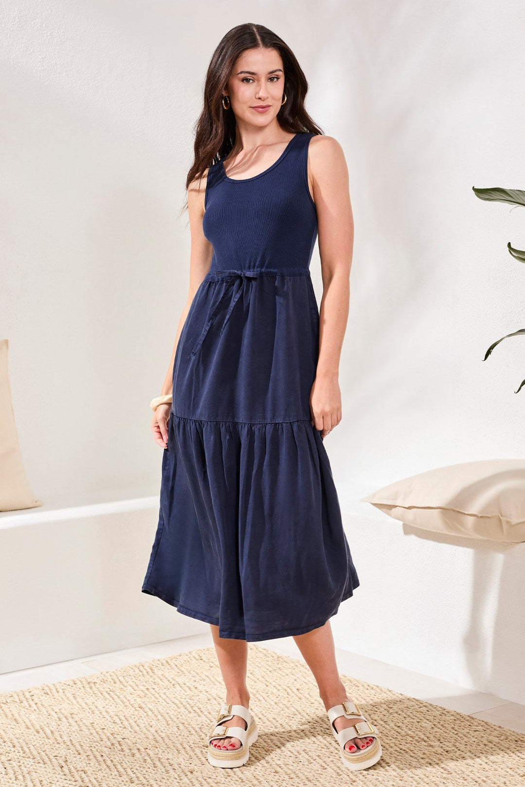 Woman wearing navy blue sleeveless midi dress with tiered ruffle hem and tie waist