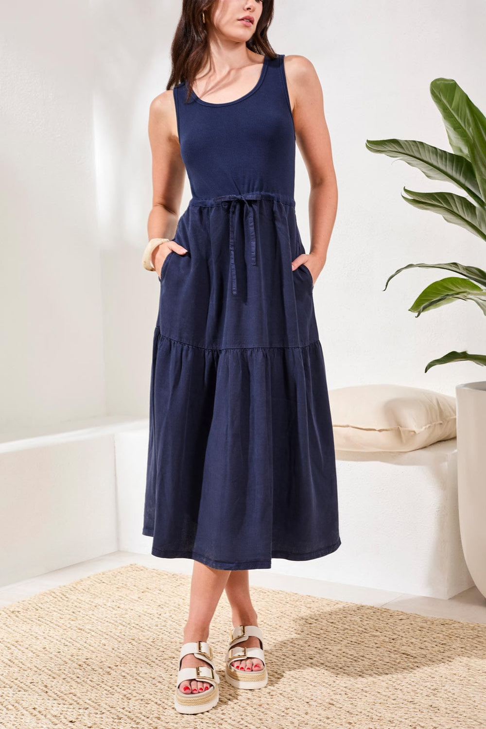 Woman wearing navy blue sleeveless tiered maxi dress with drawstring waist and pockets