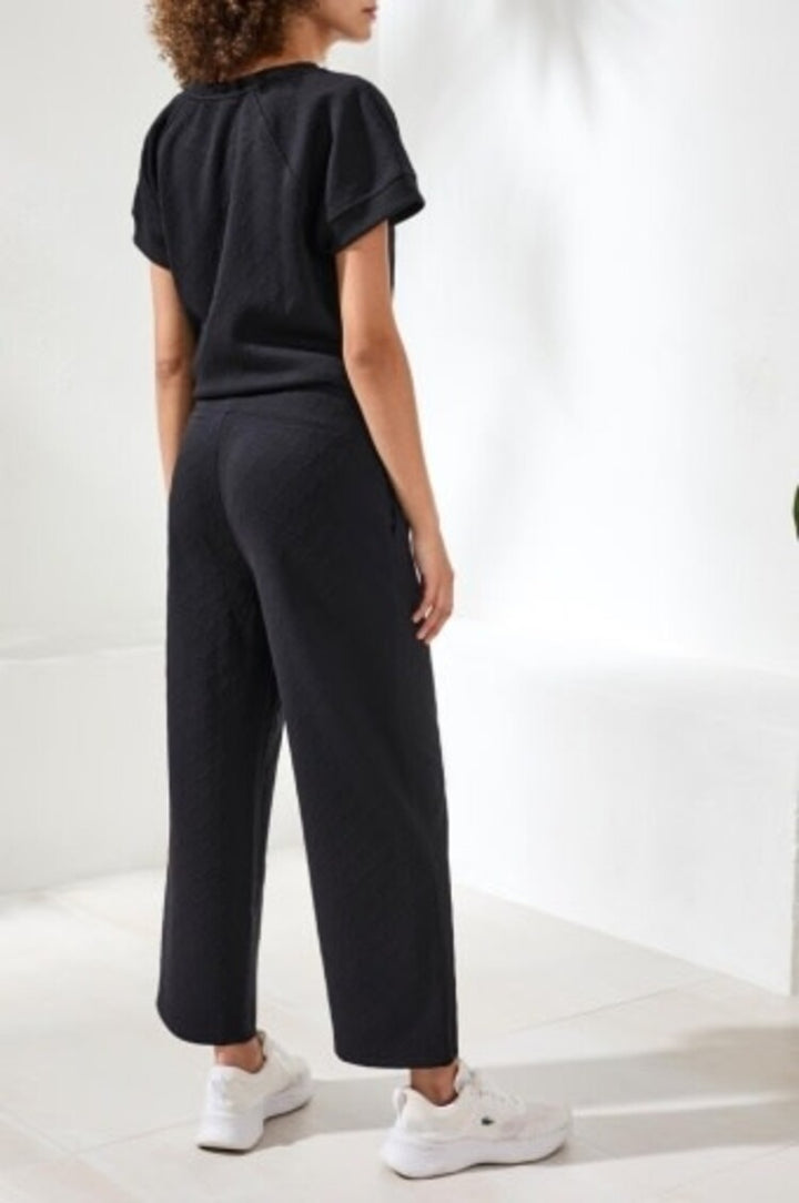 Woman wearing black pull-on capri pants with pockets and matching top, back view